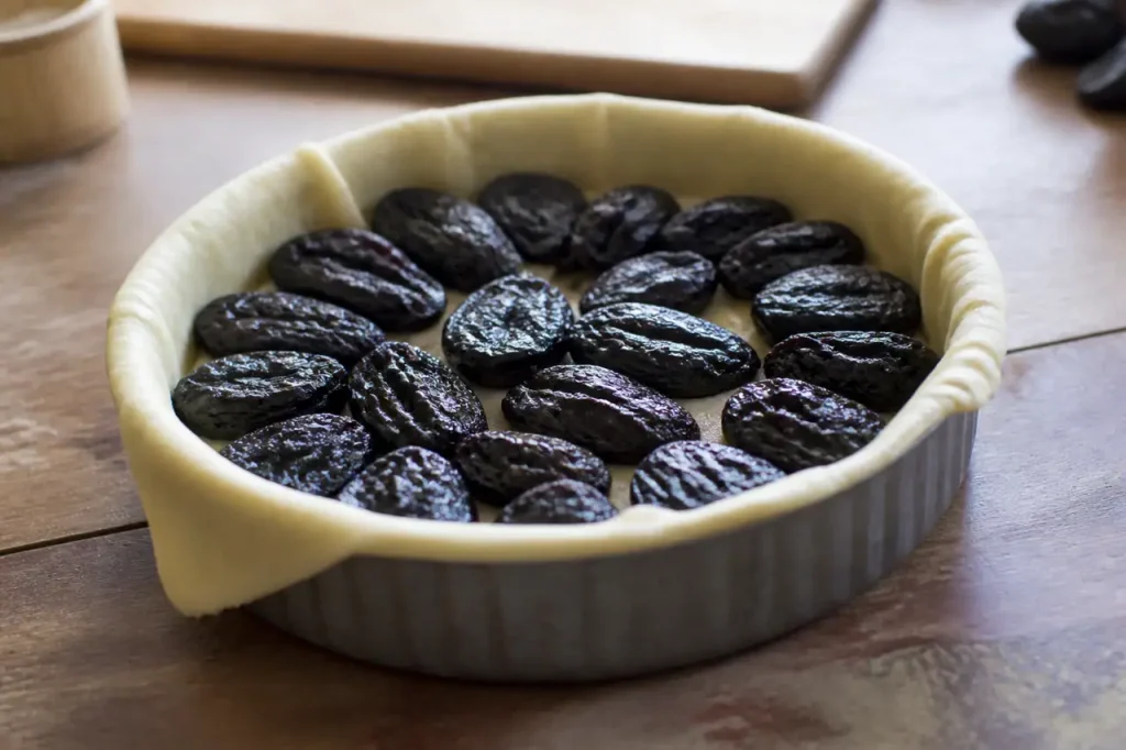 Moule rond garni de pruneaux sur une pate